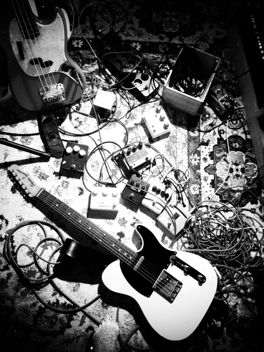 Guitares, pédales et câbles sur le tapis du studio